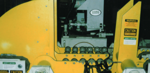 Close-up of yellow industrial machinery with safety warning labels and rollers.