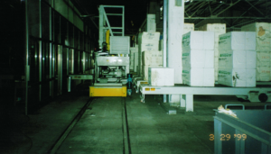 A forklift moving pallets in a spacious industrial warehouse.