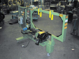 Green industrial machine with a large circular frame on wheels, likely for handling or cutting materials.