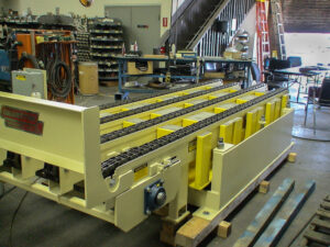 A yellow conveyor system labeled Cranston in an industrial workshop.