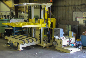 Large industrial machine with yellow parts and a flat bed, used for material handling in a workshop.