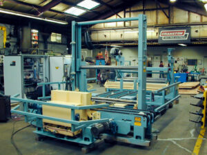 Large blue industrial machine in a workshop, likely used for fabric or material processing.