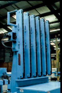 Tall blue industrial machine with multiple vertical slots in a factory.