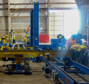 Two workers adjust equipment in a large industrial warehouse.