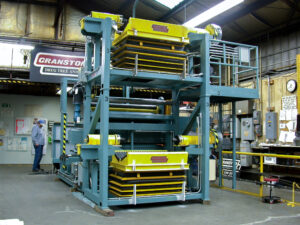 Large blue and yellow industrial machine in a workshop, likely for fabric processing or material handling.