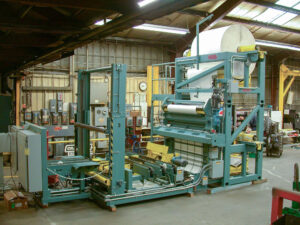 Large blue industrial machine with a roll of material, likely used for fabric processing in a workshop.